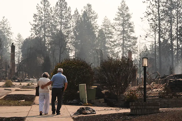 Miriam-Sim-76-walks-with-husband-Daniel-Sim-76-as-they-leave-their-burned-neighborhood-after-viewing-the-remains-of-their-home-after-a-wildfire-hit-the-northern-part-of-Spokane-Wash-Monday-Aug-3-2026