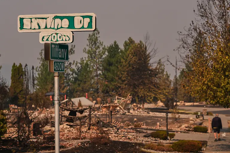 A-street-sign-shows-sign-of-fire-damage-as-a-person-walks-their-dog-after-a-wildfire-hit-the-northern-part-of-Spokane-Wash-Monday-Aug-3-2026
