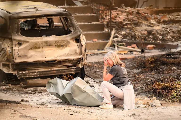 A-woman-mourns-next-to-a-deceased-dog-at-a-burned-home-during-the-Old-Trails-fire-in-Spokane-Washington-on-August-4-2026-US-authorities-arrested-a-man-on-August-3-2026-on-suspicion-of-arson-in-connection-with-the-biggest-of-three-fires-burning-around-the-northwestern-city-of-Spokane-as-firefighters-raced-to-contain-flames-that-have-displaced-tens-of-thousands-Wildfires-supercharged-by-drought-and-intense-heat-have-torn-through-the-city-in-Washington-state-burning-thousands-of-acres-and-reducing-hundreds-of-buildings-to-cinders-while-anxious-families-await-news-on-when-they-can-return