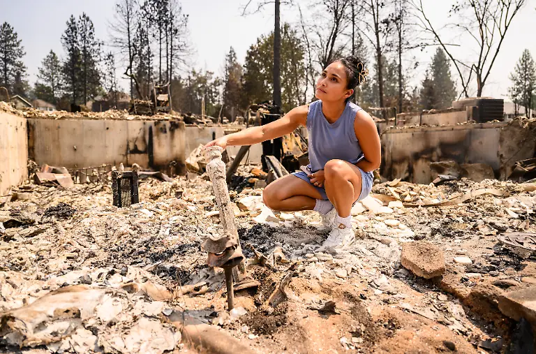A-woman-searches-for-belongings-in-the-remnants-of-her-home-burned-during-the-Old-Trails-fire-in-Spokane-Washington-on-August-4-2026-Emergency-crews-on-Tuesday-were-racing-to-contain-flames-in-the-US-Northwest-where-a-man-was-arrested-on-suspicion-of-arson-in-connection-with-the-largest-of-the-fires-that-have-displaced-tens-of-thousands-Wildfires-supercharged-by-drought-and-intense-heat-have-torn-through-the-city-of-Spokane-in-Washington-state-burning-thousands-of-acres-and-reducing-hundreds-of-buildings-to-cinders-while-anxious-families-await-news-on-when-they-can-return