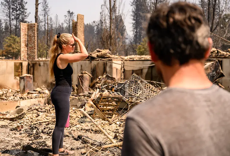 A-woman-views-her-home-burned-during-the-Old-Trails-fire-in-Spokane-Washington-on-August-4-2026-Emergency-crews-on-Tuesday-were-racing-to-contain-flames-in-the-US-Northwest-where-a-man-was-arrested-on-suspicion-of-arson-in-connection-with-the-largest-of-the-fires-that-have-displaced-tens-of-thousands-Wildfires-supercharged-by-drought-and-intense-heat-have-torn-through-the-city-of-Spokane-in-Washington-state-burning-thousands-of-acres-and-reducing-hundreds-of-buildings-to-cinders-while-anxious-families-await-news-on-when-they-can-return