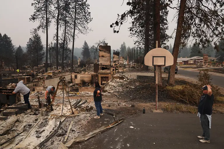 From-left-homeowner-Al-Acosta-his-son-Louis-Acosta-daughter-Renee-Stewart-and-son-in-law-Jamie-Stewart-look-through-the-remains-of-Al-s-home-after-a-wildfire-hit-the-northern-part-of-Spokane-Wash-Monday-Aug-3-2026