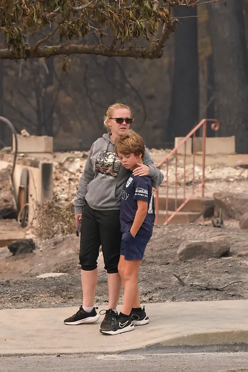 Jana-Jensen-surveys-the-neighborhood-where-her-childhood-home-owned-by-her-parents-was-lost-to-wildfire-while-embracing-her-son-Aaren-8-in-Spokane-Washington-U-S-August-2-2026