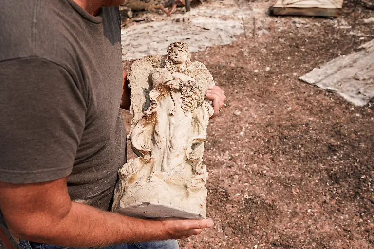 Tim-Hansen-carries-a-statuette-of-an-angel-retrieved-from-the-debris-of-a-home-that-burned-in-the-Old-Trails-Fire-in-Spokane-Washington-U-S-August-3-2026