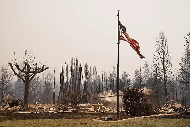 A-torn-American-flag-flutters-among-incinerated-neigbourhood-in-the-Old-Trails-Fire-in-Spokane-Washington-U-S-August-3-2026