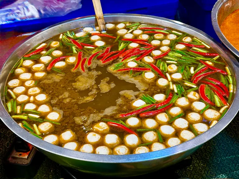 Eine-scharfe-Reisnudelsuppe-mit-Fisch-steht-in-Bangkok-am-fruehen-Morgen-auf-einem-Markt