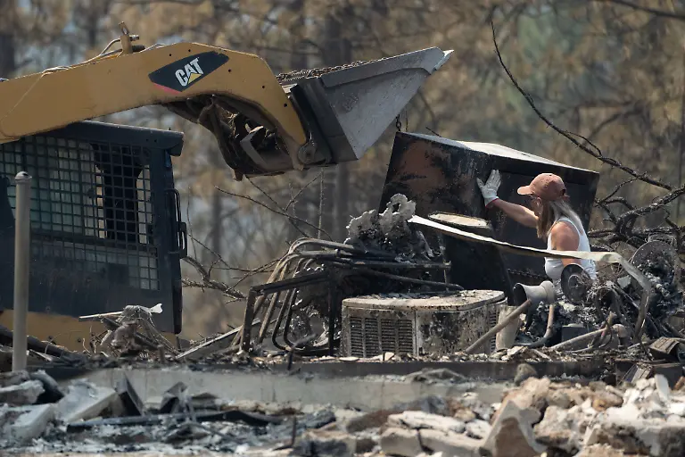 A-woman-helps-remove-a-gun-safe-from-a-home-destroyed-by-the-Old-Trails-fire-in-Spokane-Washington-U-S-August-4-2026