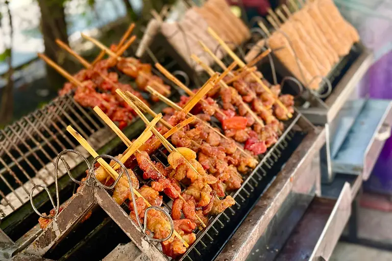 Marinierte-Schweinespiesse-stehen-an-einem-Strassenstand-in-Bangkok-zum-Verkauf-Die-Spiesse-sind-ein-beliebtes-Gericht-zum-Fruehstueck
