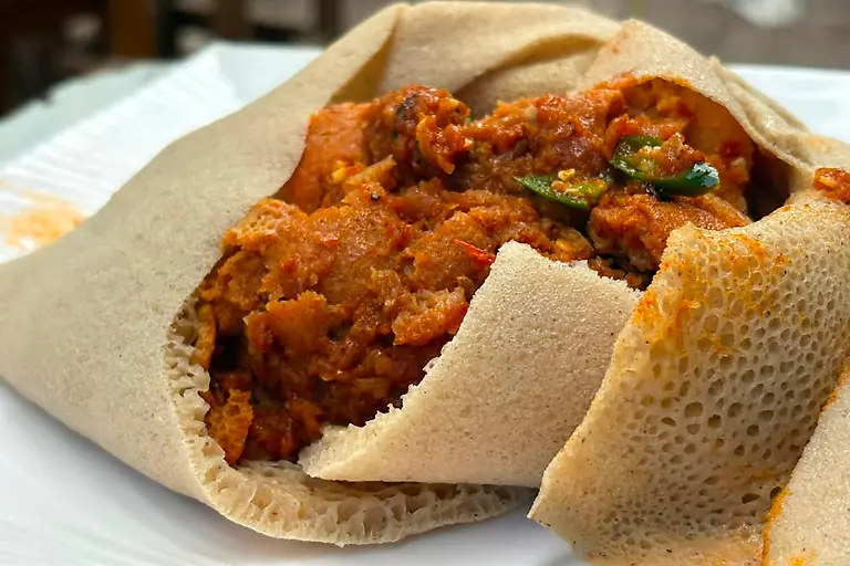 Fir-Fir-liegt-auf-einem-Teller-in-Ayat-einem-Vorort-von-Addis-Abeba-Die-Basis-des-Fruehstuecks-Gerichts-ist-zerkleinertes-Injera-das-beruehmte-sauer-weiche-Fladenbrot-der-aethiopischen-Kueche-vermengt-mit-gewuerztem-Butterschmalz-Chili-Paste-und-Eintopf-Resten-aus-Gemuese-und-Fleisch