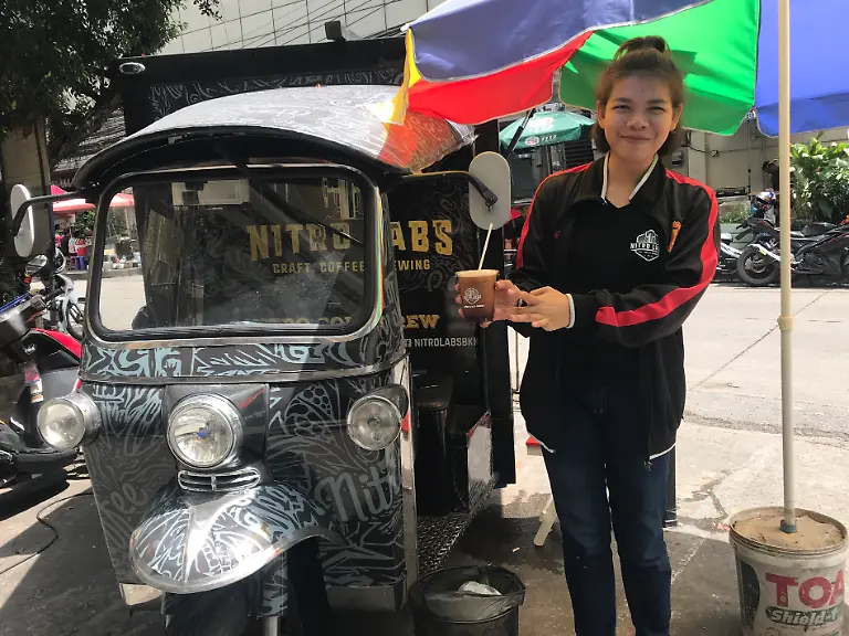 21-07-2018-Thailand-Bangkok-Eine-Verkaeuferin-bietet-an-einer-als-Coffee-Shop-umgebauten-Auto-Rikscha-namens-Tuk-Tuk-Eiskaffee-an-In-Bangkok-sind-inzwischen-einige-Tuk-Tuks-als-fahrende-Coffee-Shops-unterwegs-zu-dpa-Kaffee-aus-der-Autorikscha-Tuk-Tuks-jetzt-auch-als-Coffee-Shops-vom-23-07