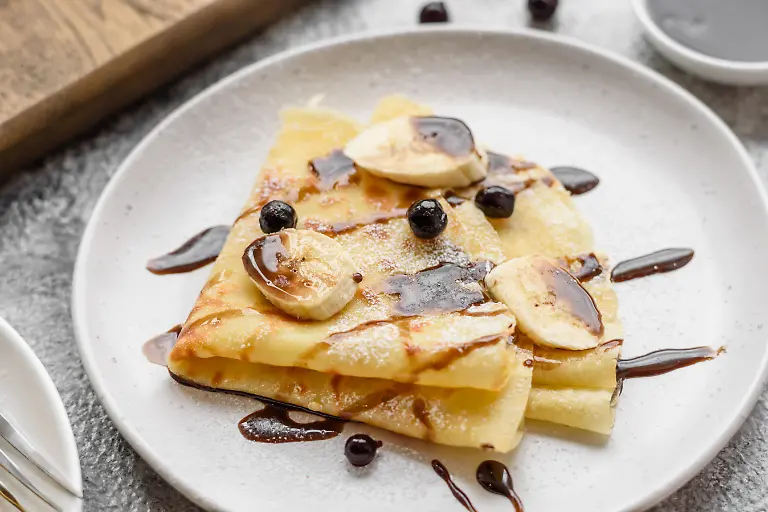 Delicious-fresh-baked-pancakes-with-honey-and-fruits-on-a-textured-concrete-background