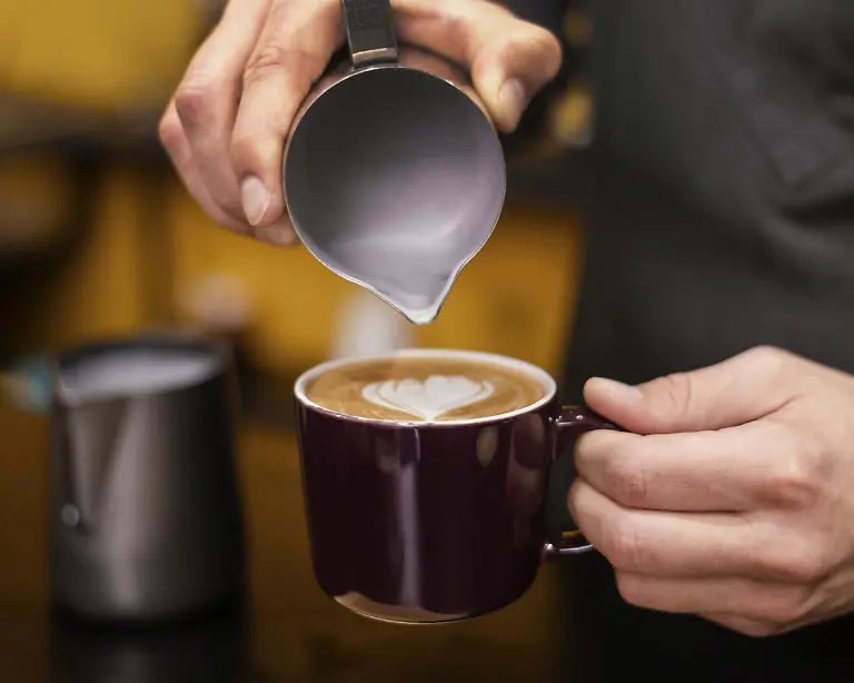 Vorderansicht-eines-maennlichen-Barista-der-eine-Tasse-Kaffee-einschenkt