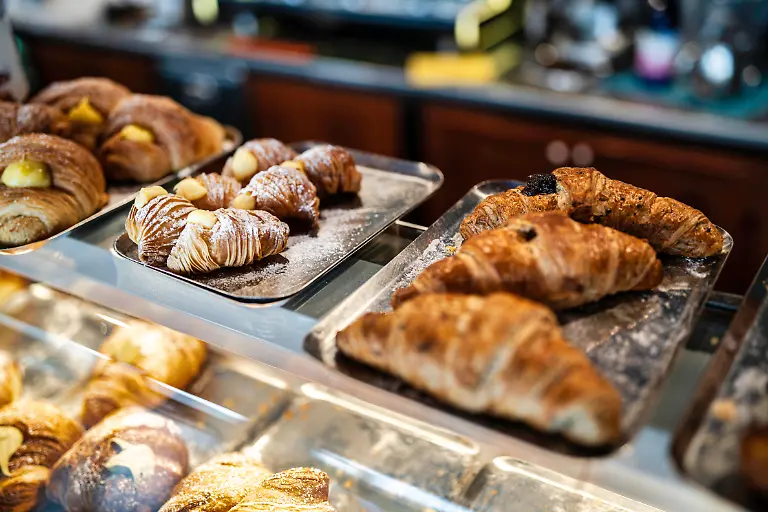 Bakery-display-case-featuring-an-assortment-of-freshly-baked-pastries-including-flaky-croissants-with-sweet-fillings-and-powdered-sugar-ready-for-breakfast-or-dessert-Bakery-display-showcasing-various-fresh-baked-pastries-Copyright-xx-road-9