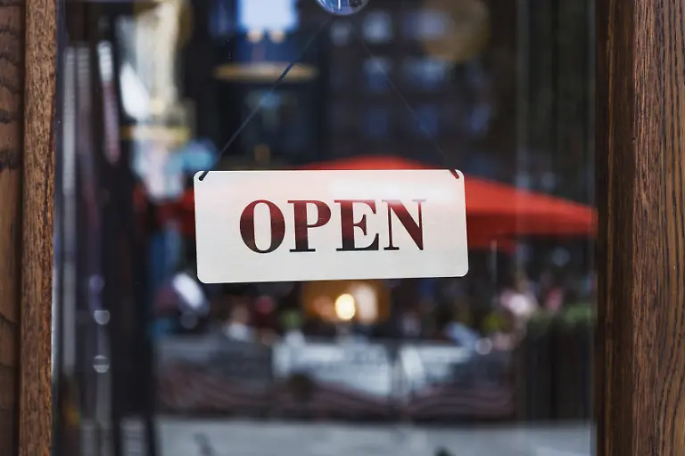 OFFENES-Schild-an-der-Glastuer-mit-verschwommenen-urbanen-Reflexionen-und-Cafe-Terrasse-im-Hintergrund-Tageslichtszene-OPEN-sign-on-glass-door-with-blurred-urban-reflections-and-cafe-patio-in-background-daylight-scene-Copyright-imageBROKER-Tartezy-ibliqx17103101