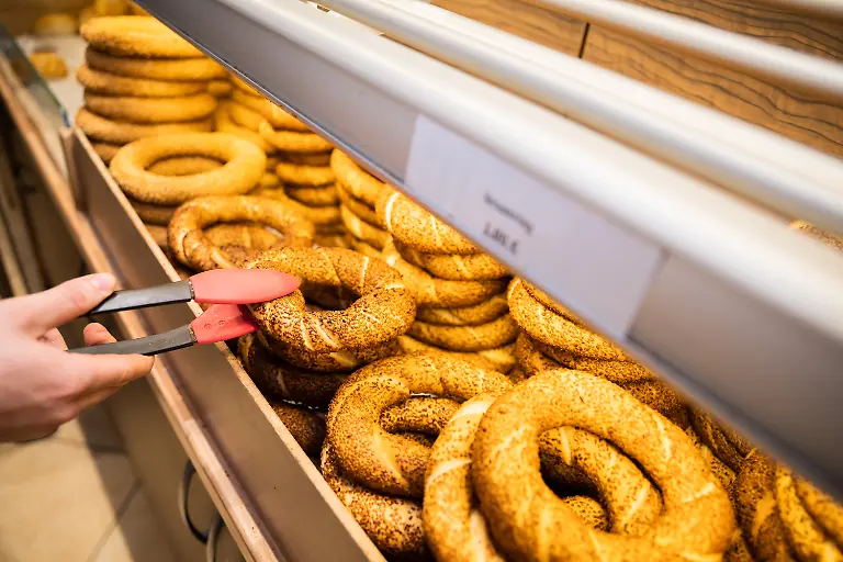 Cuma-Cevik-Geselle-und-Sohn-des-Baeckereiinhabers-Mehmet-Cevik-befuellt-die-Theke-in-der-tuerkischen-Cevik-Baeckerei-in-Berlin-Wedding-mit-frischgebackenen-Simit-Ein-Simit-ist-ein-ringfoermiges-Hefeteiggebaeck-mit-Sesamkoernern-auf-der-Kruste