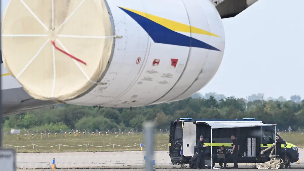 Kriminaltechniker-der-Polizei-hinten-r-bereiten-den-Einsatz-eines-Sprengroboters-in-der-Naehe-eines-ukrainischen-Flugzeugs-auf-dem-Flughafen-Leipzig-Halle-vor-Die-saechsische-Polizei-hat-die-Ermittlungen-zum-naechtlichen-Drohnen-Vorfall-am-Flughafen-Leipzig-Halle-uebernommen