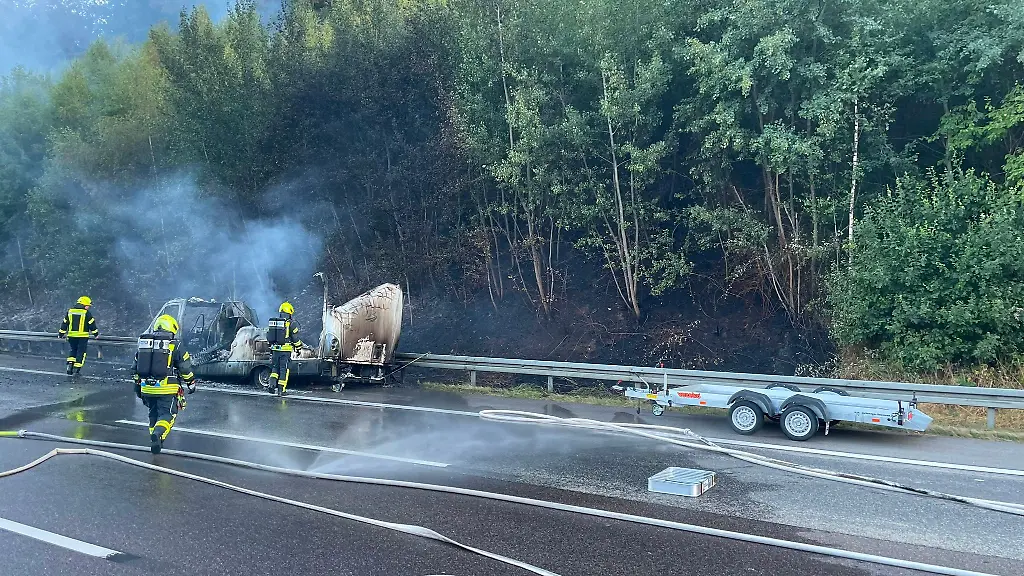 Feuerwehrleute-loeschen-das-brennende-Wohnmobil-und-den-angrenzenden-Wald