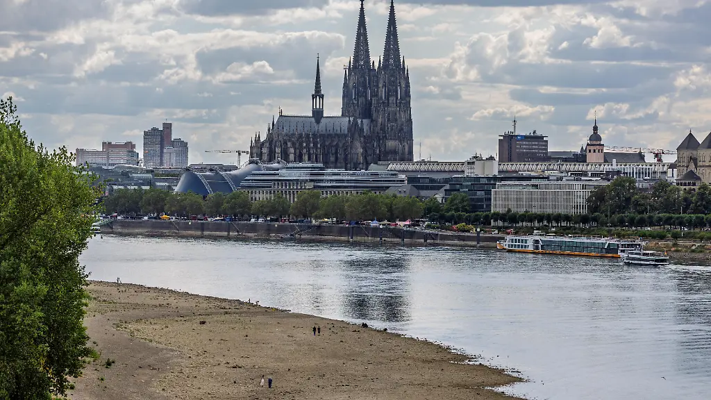 Blick-von-der-Zoobruecke-in-Koeln-auf-das-ausgetrocknete-Flussbett-des-Rheins-im-Hintergrund-der-Koelner-Dom-Mit-einem-Pegelstand-von-69-cm-am-Pegel-Koeln-erreicht-das-Niedrigwasser-den-bisherigen-historischen-Tiefstwert-vom-23-Oktober-2018-ein-neuer-Rekord-rueckt-in-greifbare-Naehe