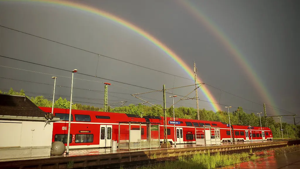 Roter-RegionalZug-am-Bahnhof-mit-doppeltem-Regenbogen-ueber-Gleisen-und-bewoelktem-Himmel-Steinbach-am-Wald-Rennsteig-Naturpark-Frankenwald-Red-regional-train-at-train-station-with-double-rainbow-over-tracks-and-cloudy-sky-Steinbach-am-Wald-Rennsteig-Frankenwald-nature-park-Park-Copyright-imageBROKER-MarcoxBunk-iblmbu17770515