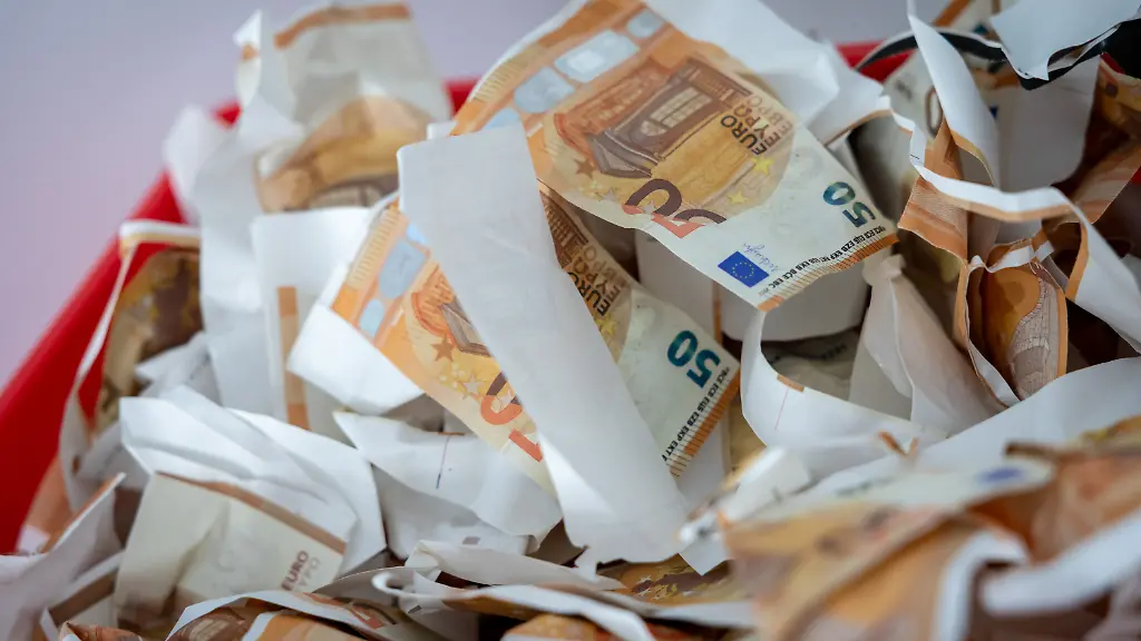 Gefaelschte-50-Euro-Scheine-von-der-Polizei-beschlagnahmt-liegen-in-einer-Kiste-waehrend-einer-Pressekonferenz-der-Kriminalpolizei-und-der-Staatsanwaltschaft-zu-Ermittlungen-in-der-Geldfaelscher-Szene-Der-nach-Polizeiangaben-bundesweit-groesste-aktive-Geldfaelscher-ist-Ermittlern-in-Bayern-und-Nordrhein-Westfalen-ins-Netz-gegangen-Der-32-Jaehrige-aus-Wuppertal-soll-zusammen-mit-seiner-Lebensgefaehrtin-seit-2023-nach-bisherigem-Ermittlungsstand-mehr-als-300-000-Euro-Falschgeld-hergestellt-und-in-den-Markt-gebracht-haben