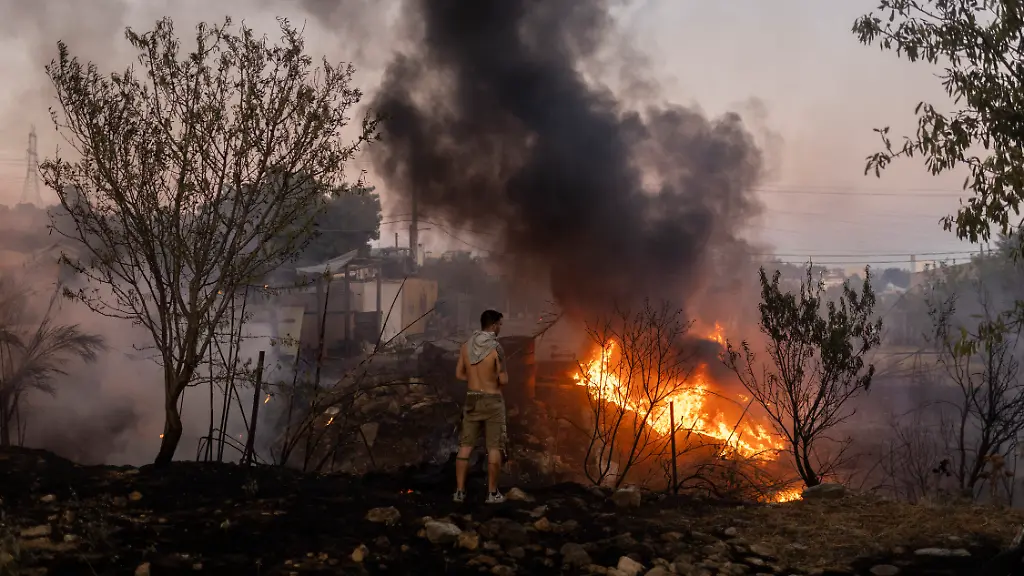 Ein-Mann-betrachtet-einen-Waldbrand-in-Ano-Patima-bei-Penteli-in-der-Region-Nord-Athen-Nur-wenige-Kilometer-nordoestlich-der-griechischen-Hauptstadt-kaempfen-Feuerwehrleute-gegen-unzaehlige-Braende-auf-einer-Flaeche-von-rund-200-Quadratkilometern-Die-Regierung-hat-nun-die-EU-um-Unterstuetzung-gebeten