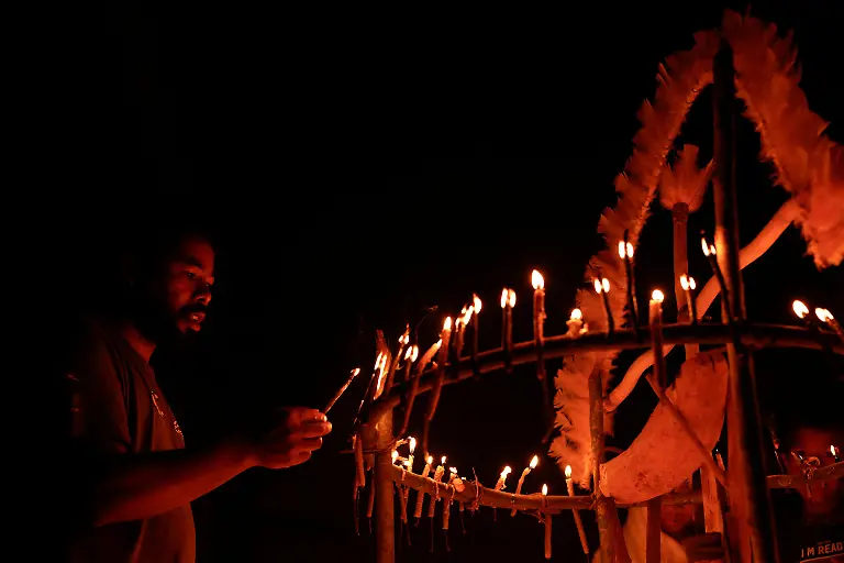 A-Guarani-Indigenous-man-holds-a-candle-during-the-Nhemongarai-a-baptism-ritual-in-the-Opy-a-Guarani-prayer-house-at-Yvy-Pora-village-Jaragua-Indigenous-Territory-in-Sao-Paulo-Brazil-January-13-2024-Each-candle-represents-the-soul-of-the-person-who-places-it-on-the-altar-of-Nhanderu-the-Creator-God-When-this-candle-is-lit-the-sacred-flame-will-reveal-each-person-s-spiritual-strength-or-it-may-also-reveal-illnesses-that-the-person-needs-to-treat-with-the-shaman-REUTERS-Amanda-Perobelli-SEARCH-PEROBELLI-BRAZIL-BEES-FOR-THIS-STORY-SEARCH-WIDER-IMAGE-FOR-ALL-STORIES