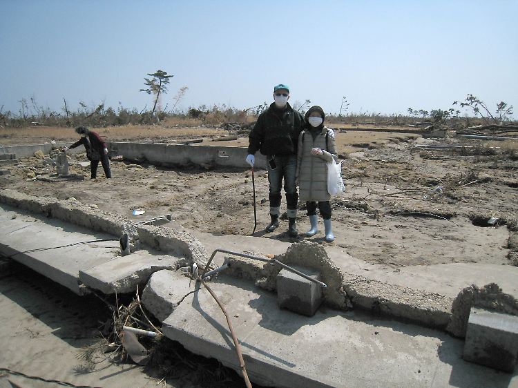 Der Deutsche Wolfgang Behrend mit seiner Ehefrau Yuko auf dem Grundstück in Yamashita, wo das Haus der Schwiegermutter Yoko Tsunoda stand. Allein das Fundament blieb.