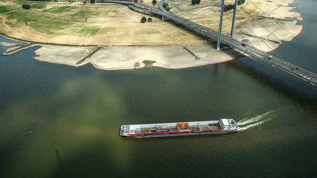Ein-Containerschiff-faehrt-mit-geringer-Ladung-bei-Niedrigwasser-am-Rheinknie-in-der-nordrhein-westfaelischen-Landeshauptstadt-vorbei-Wenn-wenig-Wasser-im-Rhein-fliesst-koennen-die-Binnenschiffe-auch-weniger-Ladung-transportieren