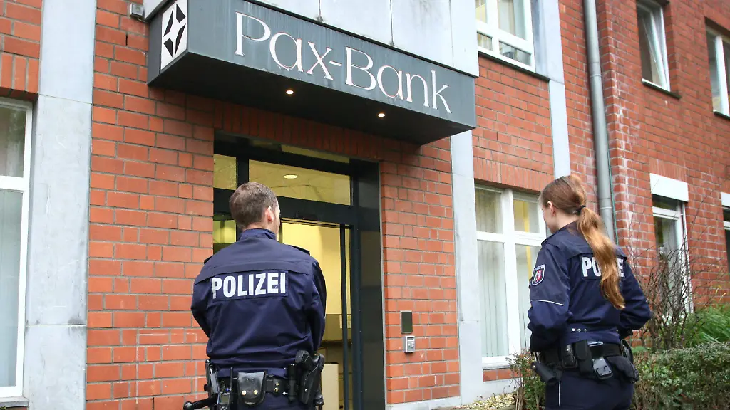 Einsatzkraefte-stehen-am-19-11-2014-in-Aachen-Nordrhein-Westfalen-vor-der-Filiale-der-Pax-Bank-Sechs-mit-Peruecken-und-Sonnenbrillen-maskierte-Bankraeuber-haben-am-Mittwoch-in-Aachen-16-Bankangestellte-bedroht-und-sind-dann-mit-ihrer-Beute-geflohen-Nach-Polizeiangaben-waren-die-dunkel-gekleideten-Raeuber-vor-der-offiziellen-Oeffnung-in-die-Bank-eingedrungen-Sie-fingen-nach-und-nach-eintreffende-Angestellte-ab-und-bedrohten-zuletzt-16-Beschaeftigte-Einige-davon-seien-gefesselt-worden-sagte-Polizeisprecher-Werner-Schneider-Mindestens-eine-Schusswaffe-sei-im-Spiel-gewesen