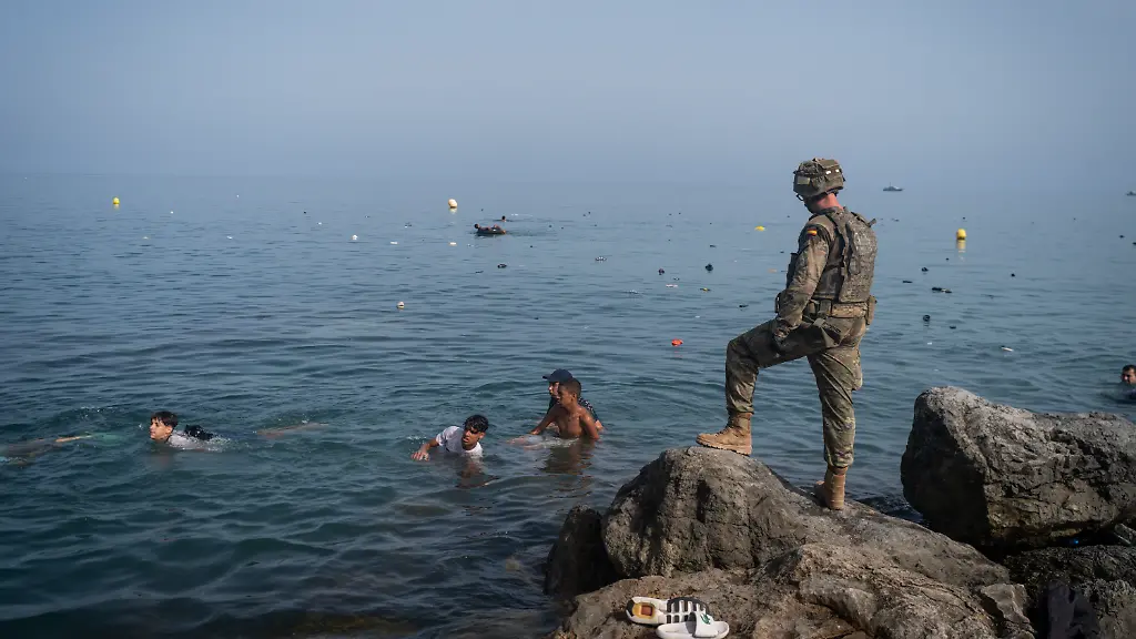 CEUTA-SPAIN-JULY-31-A-member-of-the-armed-services-watches-over-migrants-crossing-the-border-between-Spain-and-Morocco-on-July-31-2026-in-Ceuta-Spain-Spain-s-interior-ministry-has-said-it-s-deploying-60-members-of-the-armed-forces-and-an-additional-30-Guardia-Civil-officers-to-Ceuta-after-tens-of-thousands-of-migrants-entered-the-Spanish-enclave-in-North-Africa-on-Thursday-A-large-number-of-people-swam-through-the-Tarajal-breakwater-to-enter-the-Spanish-territory-from-neighboring-Morocco-while-others-scaled-the-border-fence-Some-estimates-have-said-that-around-49-000-migrants-made-the-crossing-with-the-surge-of-arrivals-overwhelming-migrant-reception-centres-with-many-sleeping-on-the-streets-overnight