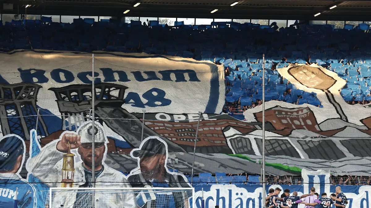 07-08-2026-Nordrhein-Westfalen-Bochum-Fussball-Maenner-2-Bundesliga-VfL-Bochum-Hertha-BSC-1-Spieltag-Vonovia-Ruhrstadion-Das-Team-des-VfL-Bochum-steht-im-Kreis-waehrend-im-Hintergrund-eine-Choreographie-der-Fans-zu-sehen-ist-Foto-David-Ebener-dpa-WICHTIGER-HINWEIS-Gemaess-den-Vorgaben-der-Bundesliga-bzw-des-DFB-Deutscher-Fussball-Bund-ist-es-untersagt-in-dem-Stadion-und-oder-vom-Spiel-angefertigte-Fotoaufnahmen-in-Form-von-Sequenzbildern-und-oder-videoaehnlichen-Fotostrecken-zu-verwerten-bzw-verwerten-zu-lassen