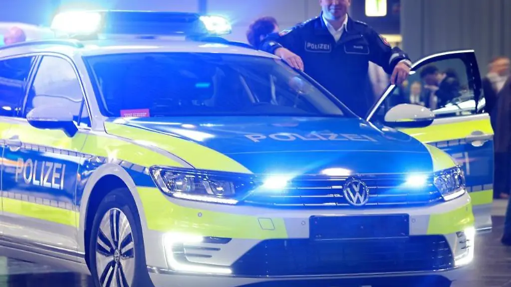 Ein-Polizist-steht-neben-einem-Hybridfahrzeug-einem-VW-Passat-GTE
