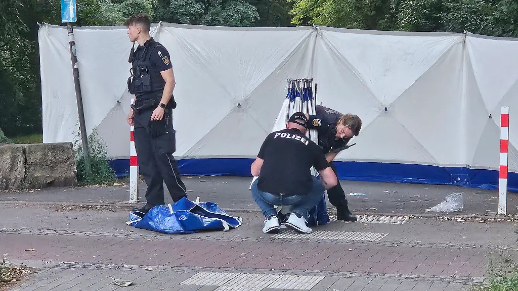 Polizisten-sichern-Spuren-am-Tatort-Nach-der-toedlichen-Auseinandersetzung-zwischen-einem-Autofahrer-und-einem-Fussgaenger-in-Bremen-wird-weiter-nach-dem-mutmasslichen-Taeter-gefahndet-Ein-56-jaehriger-Fussgaenger-war-am-Samstag-im-Stadtteil-Neustadt-von-einem-Fahrer-geschlagen-worden-Der-Mann-stuerzte-schlug-mit-dem-Kopf-auf-den-Boden-und-starb-noch-vor-Ort