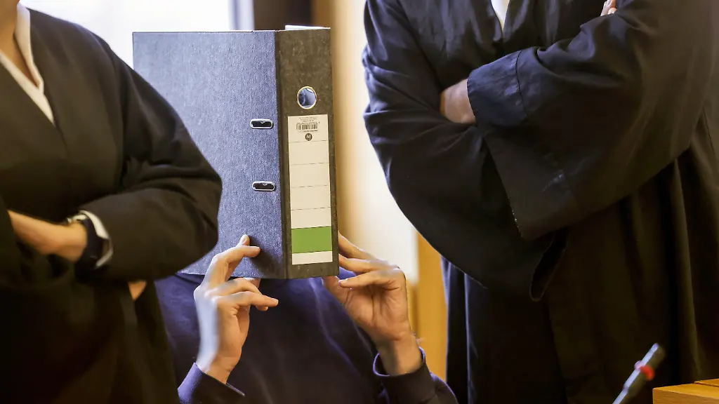 ARCHIV-05-11-2025-Nordrhein-Westfalen-Aachen-Der-Angeklagte-Krankenpfleger-M-sitzt-mit-einem-Aktenordner-vor-dem-Gesicht-im-Gerichtssaal-Das-Aachener-Landgericht-hat-einen-Krankenpfleger-wegen-des-Mordes-an-zehn-Patienten-zu-einer-lebenslangen-Freiheitsstrafe-verurteilt