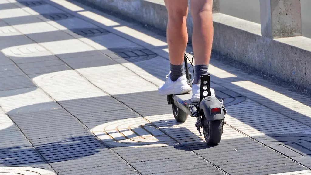 E-Scooter-im-Strassenverkehr-jugendliche-Person-faehrt-mit-einem-Elektroroller-modernes-Fortbewegungsmittel-in-der-Stadt