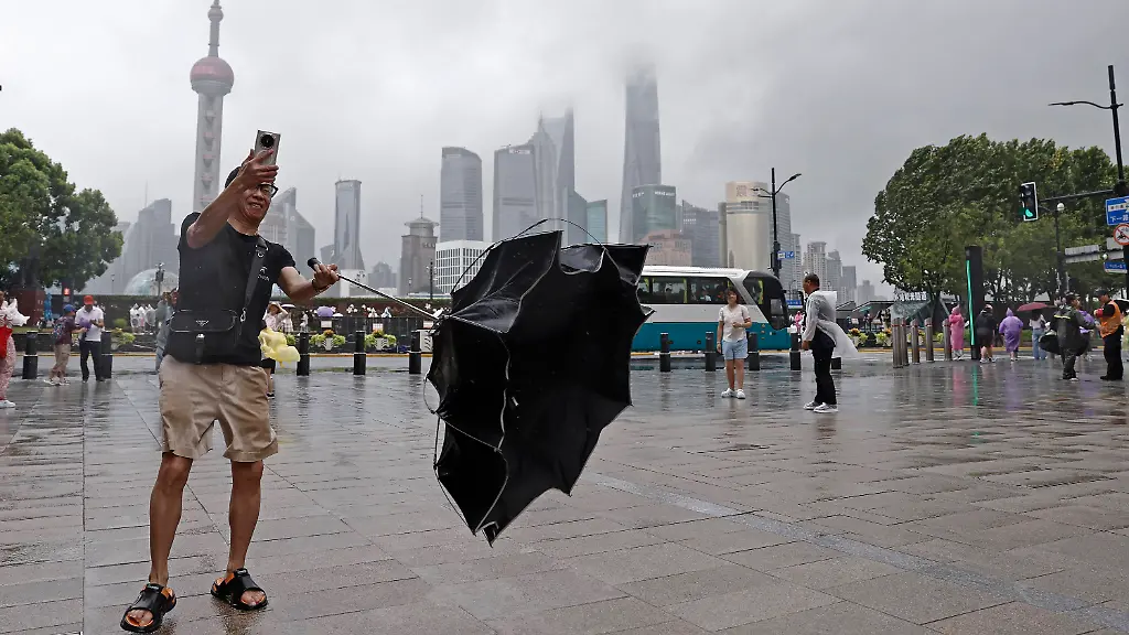 SHANGHAI-CHINA-AUGUST-09-A-tourist-takes-photos-with-mobile-phone-while-experiencing-strong-winds-on-the-Bund-on-August-9-2026-in-Shanghai-China-The-Shanghai-Meteorological-Observatory-upgraded-the-rainstorm-warning-signal-for-the-central-urban-area-from-orange-to-red-at-10-30-a-m-due-to-the-impact-of-Typhoon-Dolphin
