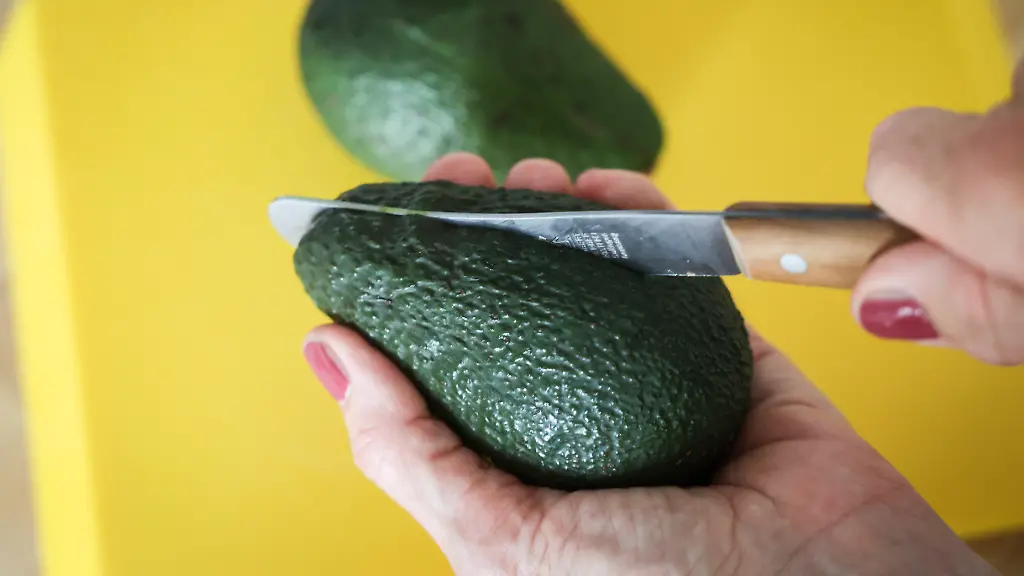 Eine-Frau-schneidet-mit-einem-Messer-eine-Avocado-auf-Die-Zahlen-zu-Faellen-von-Schnittverletzungen-beim-Aufschneiden-von-Avocados-sind-gestiegen