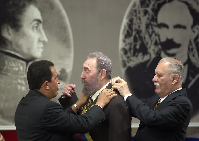 Cuban-President-Fidel-Castro-center-is-decorated-with-the-Liberator-Order-by-Venezuelan-President-Hugo-Chavez-left-and-Venezuelan-Foreign-Minister-Jose-Rangel-after-signing-a-controversial-oil-assistance-pact-at-the-Miraflores-Presidential-Palace-in-Caracas-Venezuela-Monday-Oct-30-2000-The-portraits-seen-behind-are-Venezuelan-independence-hero-Simon-Bolivar-left-and-Cuban-independence-hero-Jose-Marti