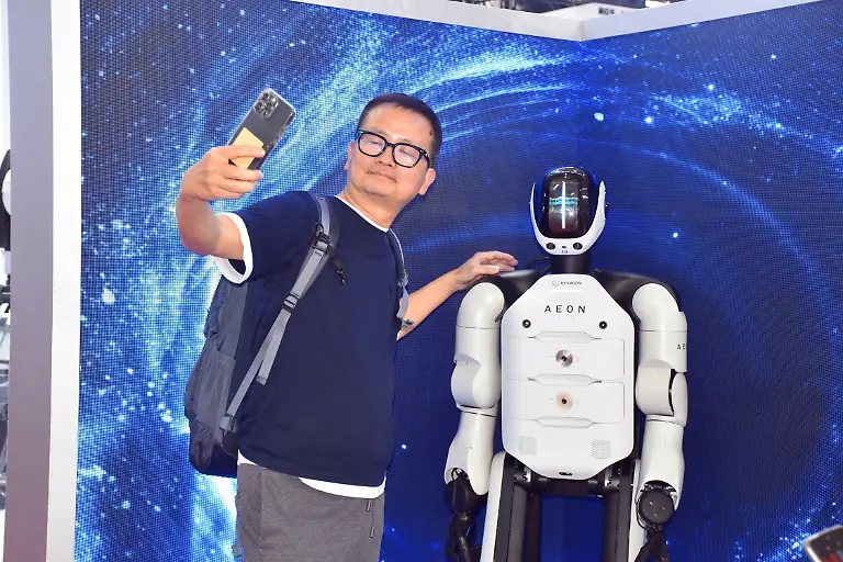 BEIJING-CHINA-AUGUST-09-A-visitor-poses-for-a-photo-with-humanoid-robot-AEON-at-the-booth-of-Hexagon-during-the-2025-World-Robot-Conference-WRC-at-Beiren-Yichuang-International-Convention-and-Exhibition-Center-on-August-9-2025-in-Beijing-China