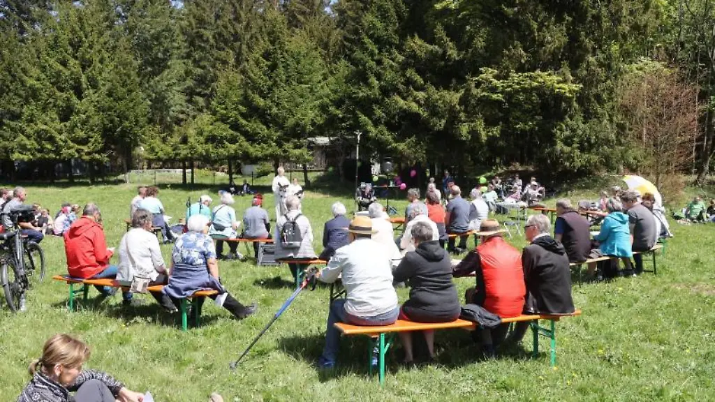 Besucher-eines-evangelischen-Gottesdienstes-sitzen-auf-einer-Wiese-auf-Baenken