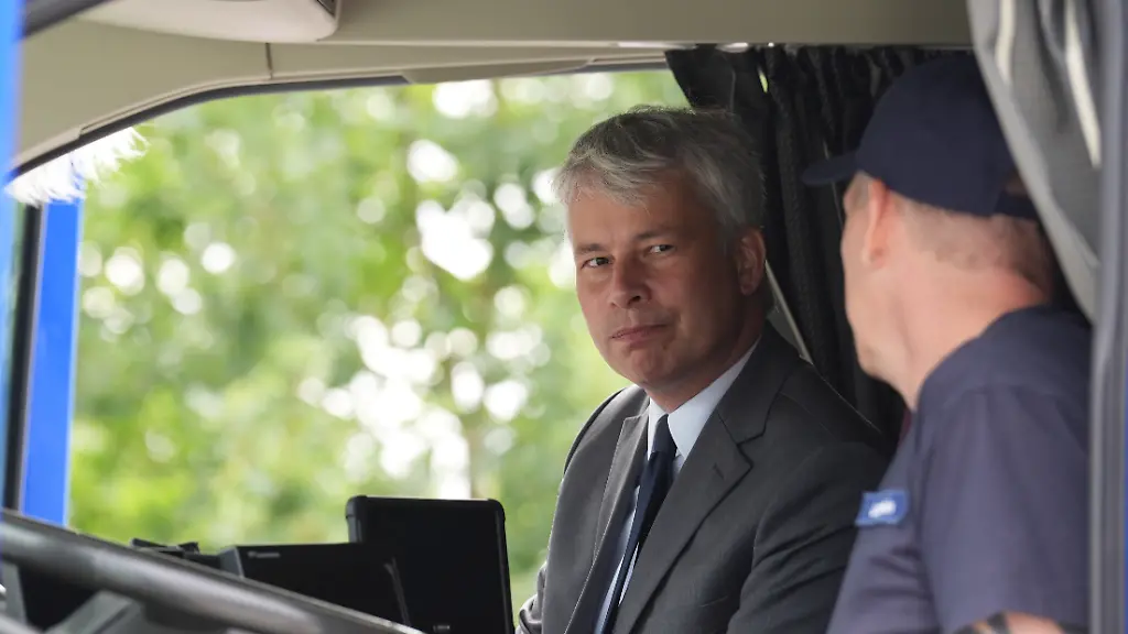 Steffen-Bilger-l-CDU-Bundesminister-fuer-Verkehr-sitzt-auf-dem-Beifahrersitz-eines-elektrischen-Lastwagens-und-spricht-mit-Lkw-Fahrer-Michael-Langhein-am-Standort-des-Lebensmittelhaendlers-Bartels-Langness-ueber-das-vom-Ministerium-gefoerderte-Projekt-Ladeinfrastruktur-fuer-E-Lkws-Verkehrsminister-Bilger-besuchte-waehrend-seiner-Sommerreise-verschiedene-Projekte-im-Norden