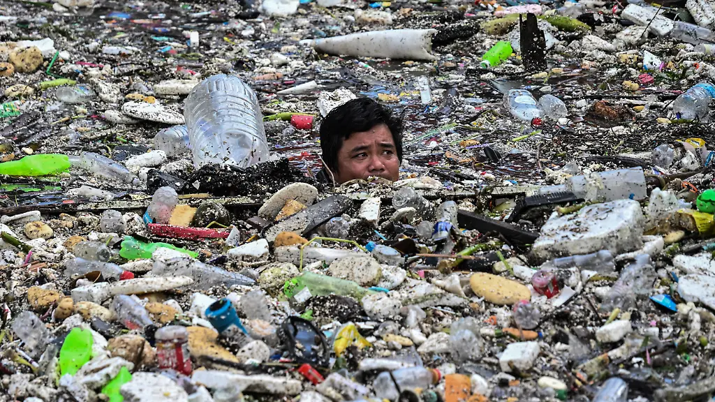 A-worker-collects-garbage-that-washed-into-a-river-amid-heavy-southwest-monsoon-rains-near-Baclaran-Church-in-Paranaque-City-Metro-Manila-Philippines-August-11-2026