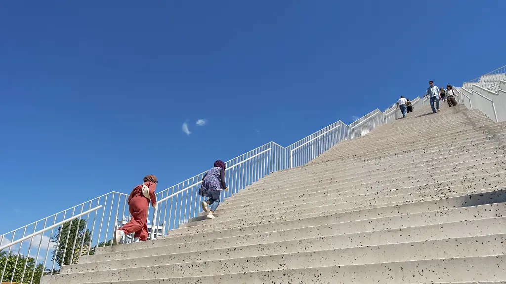 Menschen-erklimmen-monumentale-Betontreppen-die-unter-strahlend-blauem-Himmel-die-renovierte-Pyramide-von-Tirana-hinauffuehren-Albanien