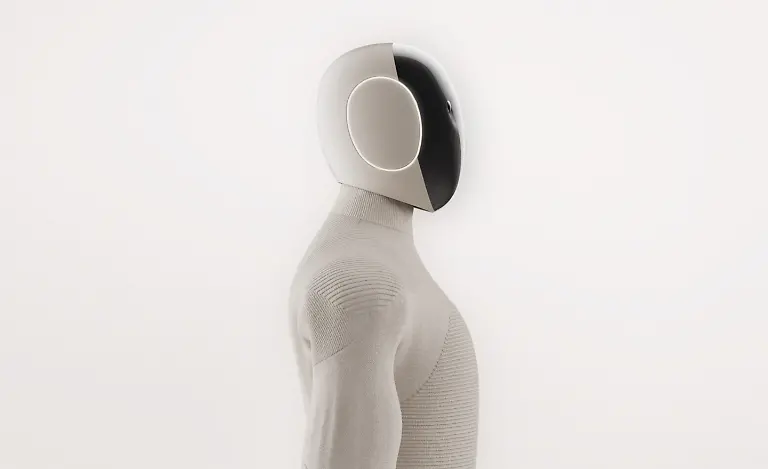 VIDEO-AVAILABLE-CONTACT-INFO-COVERMG-COM-TO-RECEIVE-A-humanoid-A-I-powered-home-help-robot-is-set-to-be-tested-in-homes-Norway-and-Silicon-Valley-based-robotics-firm-1X-has-unveiled-its-latest-humanoid-robot-Neo-Gamma-It-is-designed-to-assist-with-household-chores-while-blending-seamlessly-into-domestic-settings-Wrapped-in-a-beige-3D-knitted-bodysuit-the-robot-aims-to-fit-into-homes-with-its-minimalist-appearance-Neo-Gamma-boasts-a-more-Scandinavian-inspired-design-and-is-equipped-to-perform-tasks-such-as-vacuuming-tidying-and-doing-the-laundry-The-robots-integrated-artificial-intelligence-system-enables-it-to-approximate-human-speech-and-body-language-enhancing-its-ability-to-interact-with-users-Neo-Gamma-s-humanoid-frame-includes-advanced-audio-and-communication-features-It-has-four-microphones-for-audio-capture-and-a-speaker-system-with-one-speaker-in-the-chest-for-AI-voice-interaction-and-two-in-the-pelvis-for-bass-sound-effects-and-music-To-improve-communication-1X-has-added-emotive-ear-rings-on-the-sides-of-the-robot-s-head-which-light-up-to-indicate-when-it-is-speaking-or-listening-The-robot-has-been-trained-using-human-motion-capture-data-allowing-it-to-walk-with-a-natural-gait-swing-its-arms-squat-and-sit-in-chairs-Images-released-by-1X-show-Neo-Gamma-performing-everyday-household-tasks-such-as-preparing-coffee-and-vacuuming-floors-Its-multi-jointed-hands-which-mimic-human-tendon-movement-are-controlled-by-elastic-motors-and-encased-in-soft-covers-for-additional-safety-While-the-Neo-Gamma-is-still-a-prototype-the-company-plans-to-begin-limited-in-home-testing-The-soft-knitted-nylon-covering-serves-both-aesthetic-and-practical-purposes-It-reduces-potential-injuries-from-robot-to-human-contact-and-helps-lower-the-robot-s-operating-noise-to-about-the-same-level-as-a-refrigerator-according-to-1X-A-significant-factor-in-Neo-Gammas-advanced-capabilities-lies-in-the-firms-partnership-with-OpenAI
