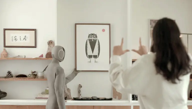 VIDEO-AVAILABLE-CONTACT-INFO-COVERMG-COM-TO-RECEIVE-A-humanoid-A-I-powered-home-help-robot-is-set-to-be-tested-in-homes-Norway-and-Silicon-Valley-based-robotics-firm-1X-has-unveiled-its-latest-humanoid-robot-Neo-Gamma-It-is-designed-to-assist-with-household-chores-while-blending-seamlessly-into-domestic-settings-Wrapped-in-a-beige-3D-knitted-bodysuit-the-robot-aims-to-fit-into-homes-with-its-minimalist-appearance-Neo-Gamma-boasts-a-more-Scandinavian-inspired-design-and-is-equipped-to-perform-tasks-such-as-vacuuming-tidying-and-doing-the-laundry-The-robots-integrated-artificial-intelligence-system-enables-it-to-approximate-human-speech-and-body-language-enhancing-its-ability-to-interact-with-users-Neo-Gamma-s-humanoid-frame-includes-advanced-audio-and-communication-features-It-has-four-microphones-for-audio-capture-and-a-speaker-system-with-one-speaker-in-the-chest-for-AI-voice-interaction-and-two-in-the-pelvis-for-bass-sound-effects-and-music-To-improve-communication-1X-has-added-emotive-ear-rings-on-the-sides-of-the-robot-s-head-which-light-up-to-indicate-when-it-is-speaking-or-listening-The-robot-has-been-trained-using-human-motion-capture-data-allowing-it-to-walk-with-a-natural-gait-swing-its-arms-squat-and-sit-in-chairs-Images-released-by-1X-show-Neo-Gamma-performing-everyday-household-tasks-such-as-preparing-coffee-and-vacuuming-floors-Its-multi-jointed-hands-which-mimic-human-tendon-movement-are-controlled-by-elastic-motors-and-encased-in-soft-covers-for-additional-safety-While-the-Neo-Gamma-is-still-a-prototype-the-company-plans-to-begin-limited-in-home-testing-The-soft-knitted-nylon-covering-serves-both-aesthetic-and-practical-purposes-It-reduces-potential-injuries-from-robot-to-human-contact-and-helps-lower-the-robot-s-operating-noise-to-about-the-same-level-as-a-refrigerator-according-to-1X-A-significant-factor-in-Neo-Gammas-advanced-capabilities-lies-in-the-firms-partnership-with-OpenAI
