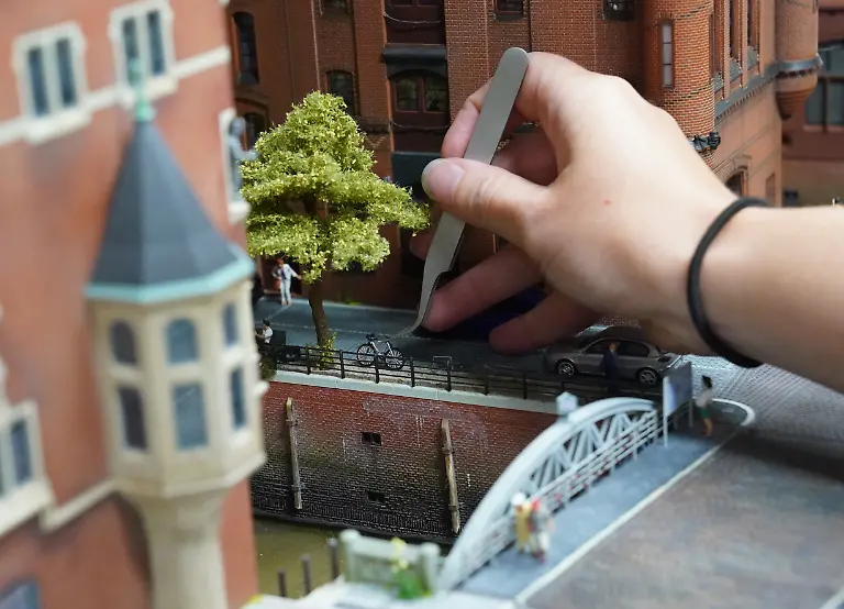Modellbauerin-Tanja-Schlabitz-setzt-mit-einer-Pinzette-ein-Fahrrad-in-die-neue-Speicherstadt-in-der-Werkstatt-des-Miniatur-Wunderlands-Die-gelernte-Tischlerin-und-Zeichnerin-arbeitet-im-Miniatur-Wunderland-in-der-Abteilung-Modellbau-und-ist-fuer-die-Erneuerung-der-Speicherstadt-zustaendig