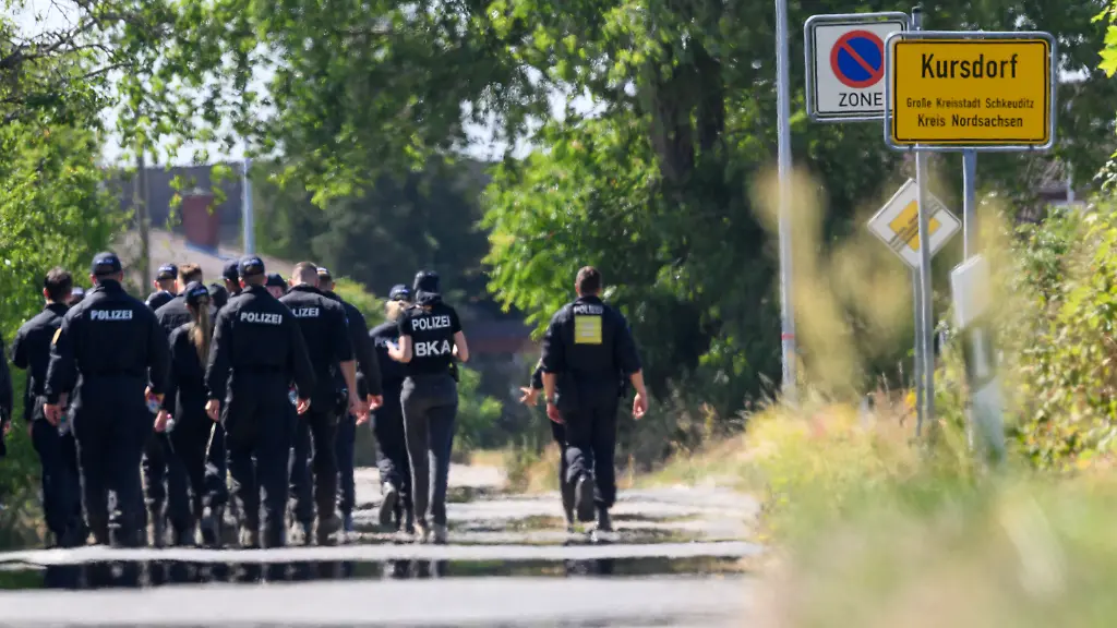 Einsatzkraefte-der-Polizei-und-des-BKA-suchen-am-Flughafen-Leipzig-Halle-nahe-dem-Ort-Kursdorf-nach-Spuren-Nach-dem-Drohnenvorfall-in-der-Nacht-zum-Mittwoch-05-08-laufen-die-Ermittlungen-Die-fuer-einen-Angriff-ausgeruestete-Drohne-war-nach-Angaben-aus-Sicherheitskreisen-nahe-einer-ukrainischen-Transportmaschine-sichergestellt-worden-Unschaerfe-durch-Hitzeflimmern-bei-Aufnahme-aus-groesserer-Distanz