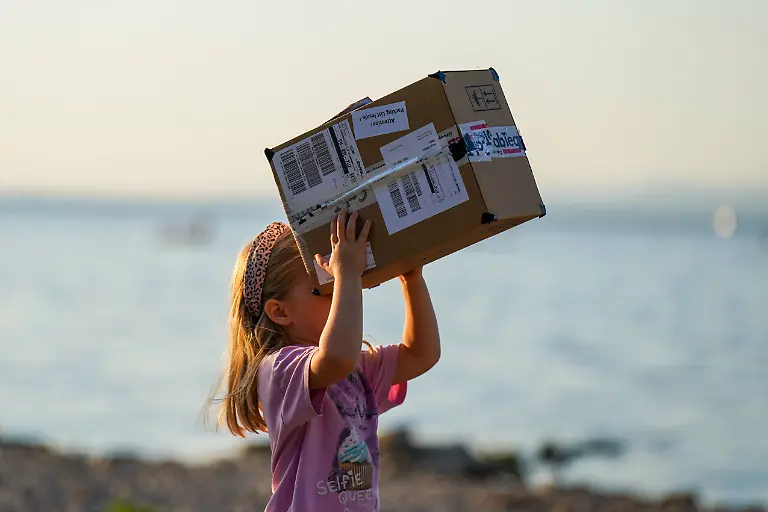 Altenrhein-Bodensee-Schweiz-Maedchen-beobachtet-eine-Sonnenfinsternis-mit-einer-selbstgebauten-Lochkamera-aus-einem-Karton-Das-Kind-richtet-die-improvisierte-Projektionshilfe-zur-Sonne-im-Hintergrund-der-Bodensee-Sonnenfinsternis-partielle-Sonnenfinsternis-Sofi-Astronomie-Sonne-Lochkamera-Projektionsmethode-Augenschutz-Kind-Maedchen-Experiment-Naturphaenomen-Wissenschaft-Altenrhein-Bodensee-St-Gallen-Schweiz-Altenrhein-Lake-Constance-Switzerland-A-girl-observes-a-solar-eclipse-using-a-homemade-pinhole-camera-made-from-a-cardboard-box-The-child-points-the-improvised-projection-device-toward-the-sun-Lake-Constance-is-visible-in-the-background