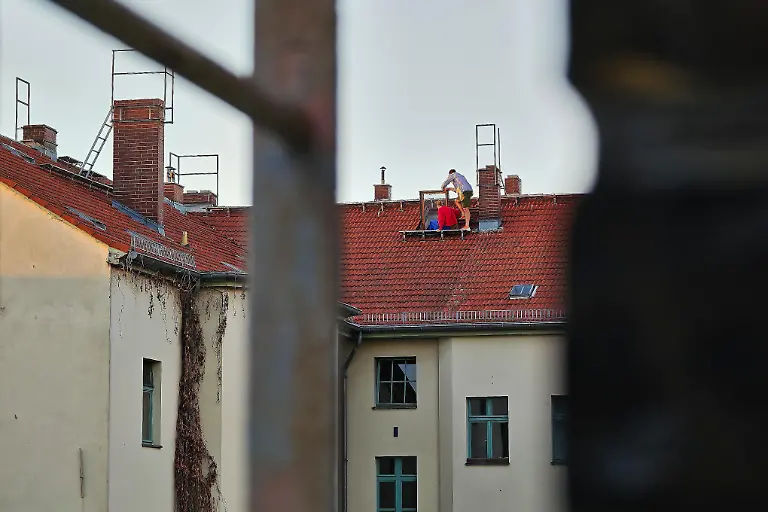 Berlin-Deutschland-Sonnenfinsternis-Im-Stadtteil-Kreuzberg-klettern-Menschen-auf-ein-Hausdach-um-das-Himmelsspektakel-zu-beobachten