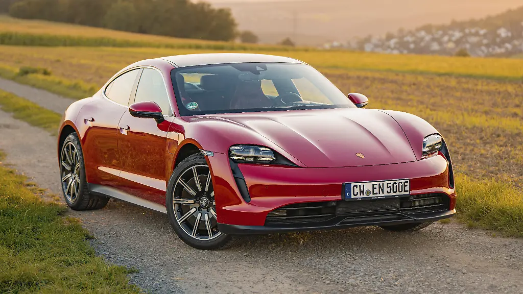 Ein-roter-Sportwagen-faehrt-auf-einem-Asphaltweg-durch-eine-laendliche-Landschaft-Porsche-Taycan-Deer-Carsharing